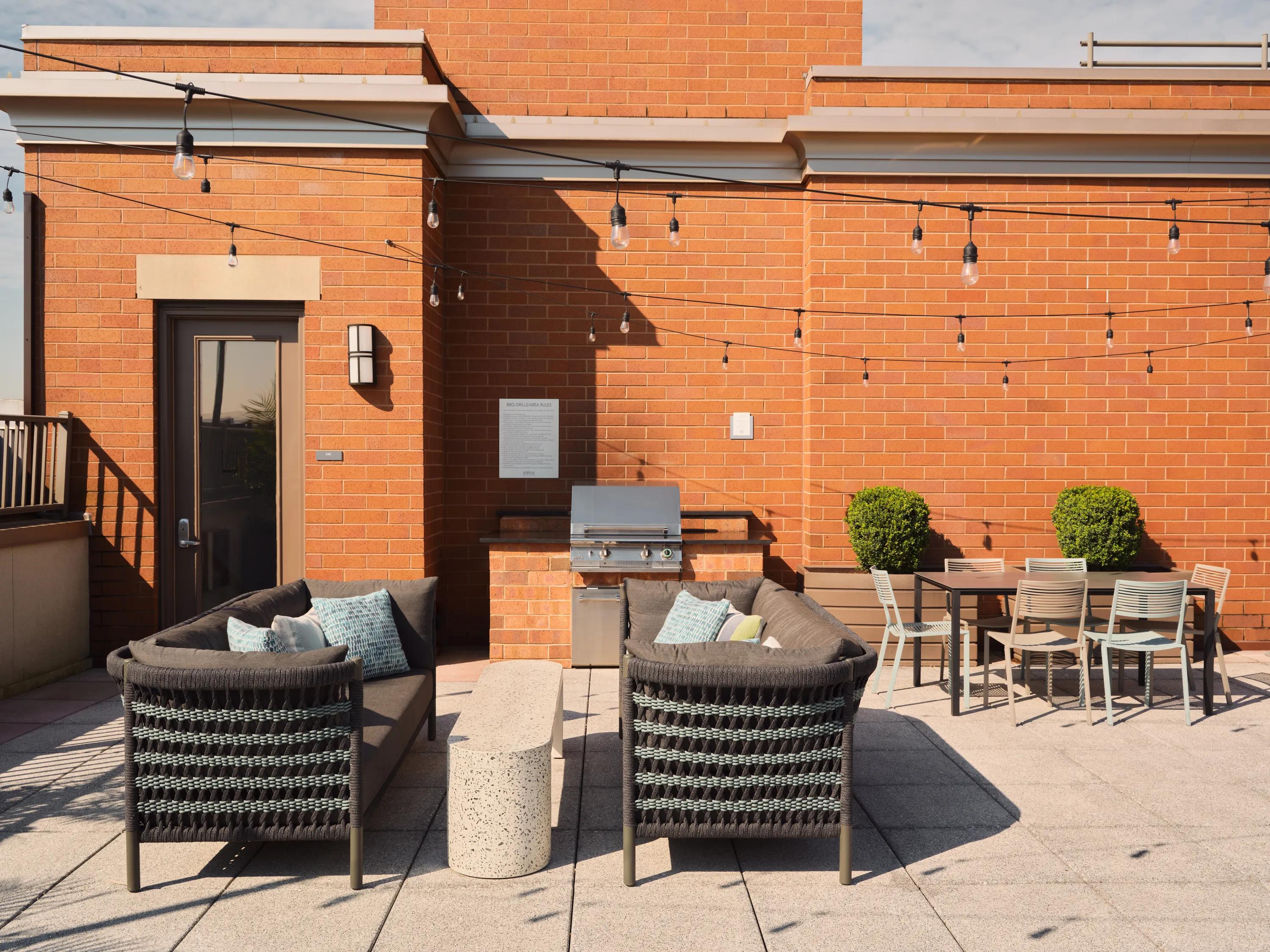 seating next to bbq grill and outdoor table on rooftop metropolitan at 40 park apartment homes for rent in morristown nj