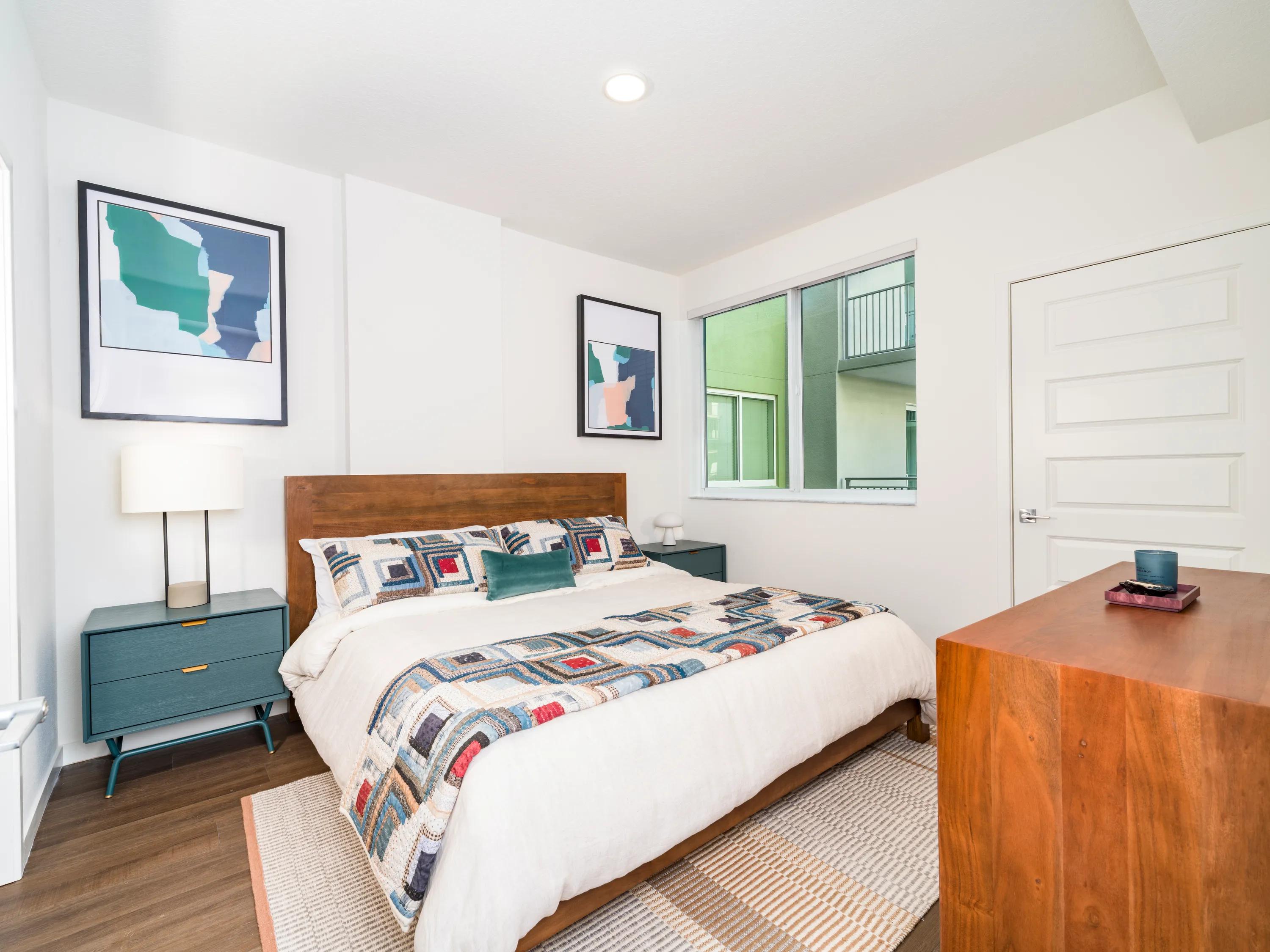 Secondary bedroom with oversized windows, wood-style flooring, contemporary finishes, and a spacious layout at Modera Encore apartments in Tampa, FL.