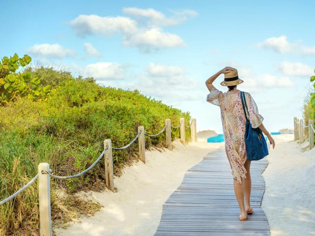 person walking to the beach through a path on the dunes 580 anton apartments in costa mesa ca near huntington beach