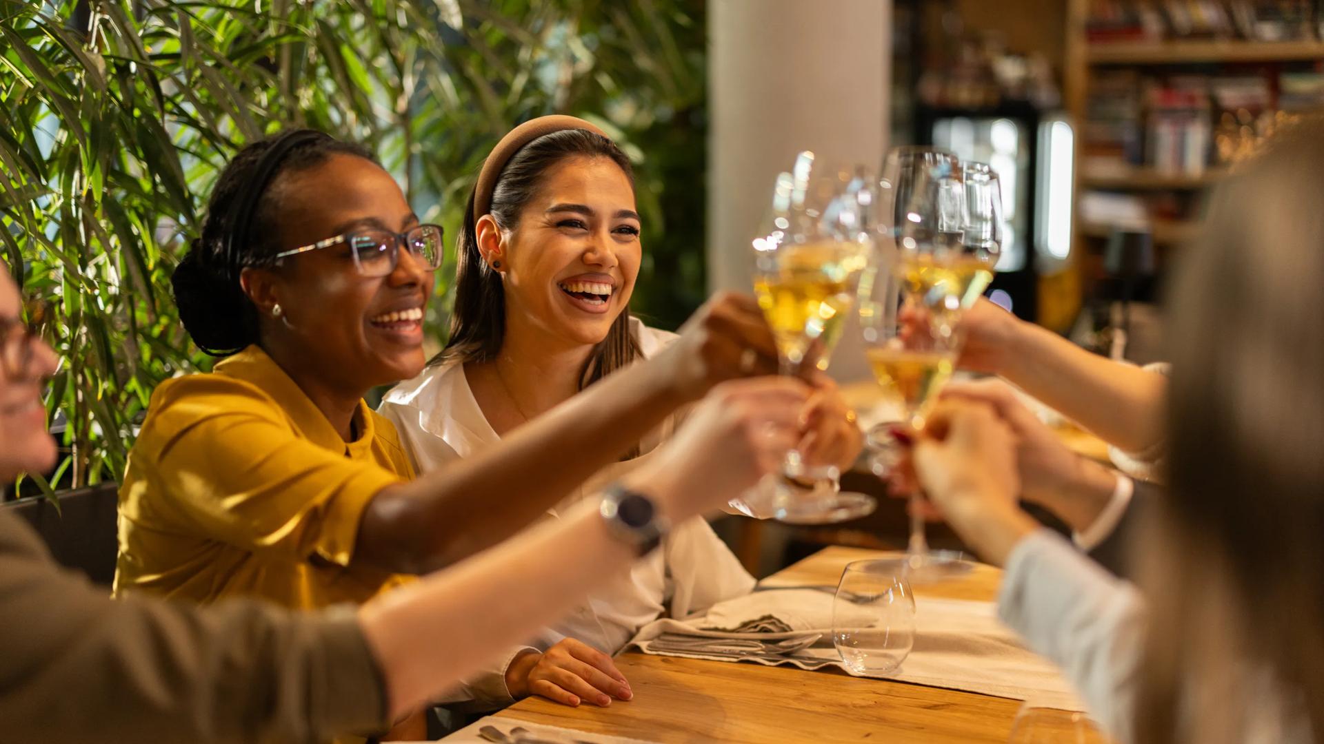 Cheerful multiracial group of guests toasting with white wine in luxury restaurant amavi nw austin homes for rent