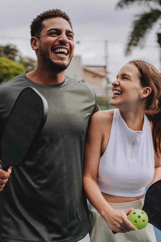 couple outside at pickleball court smiling and embracing modera st paul apartments in dallas
