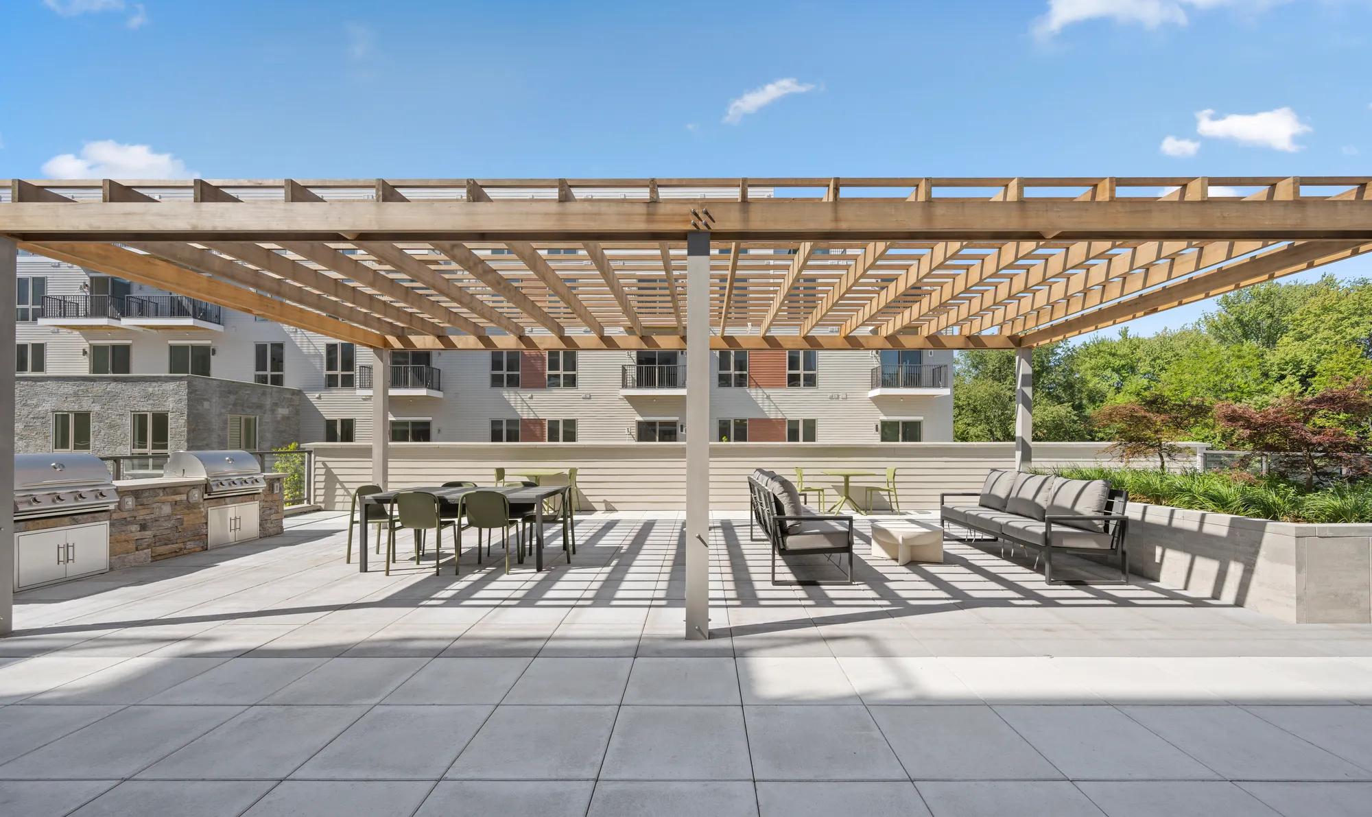 outdoor dining space with tables and covering at modera newton apartment homes for rent in ma