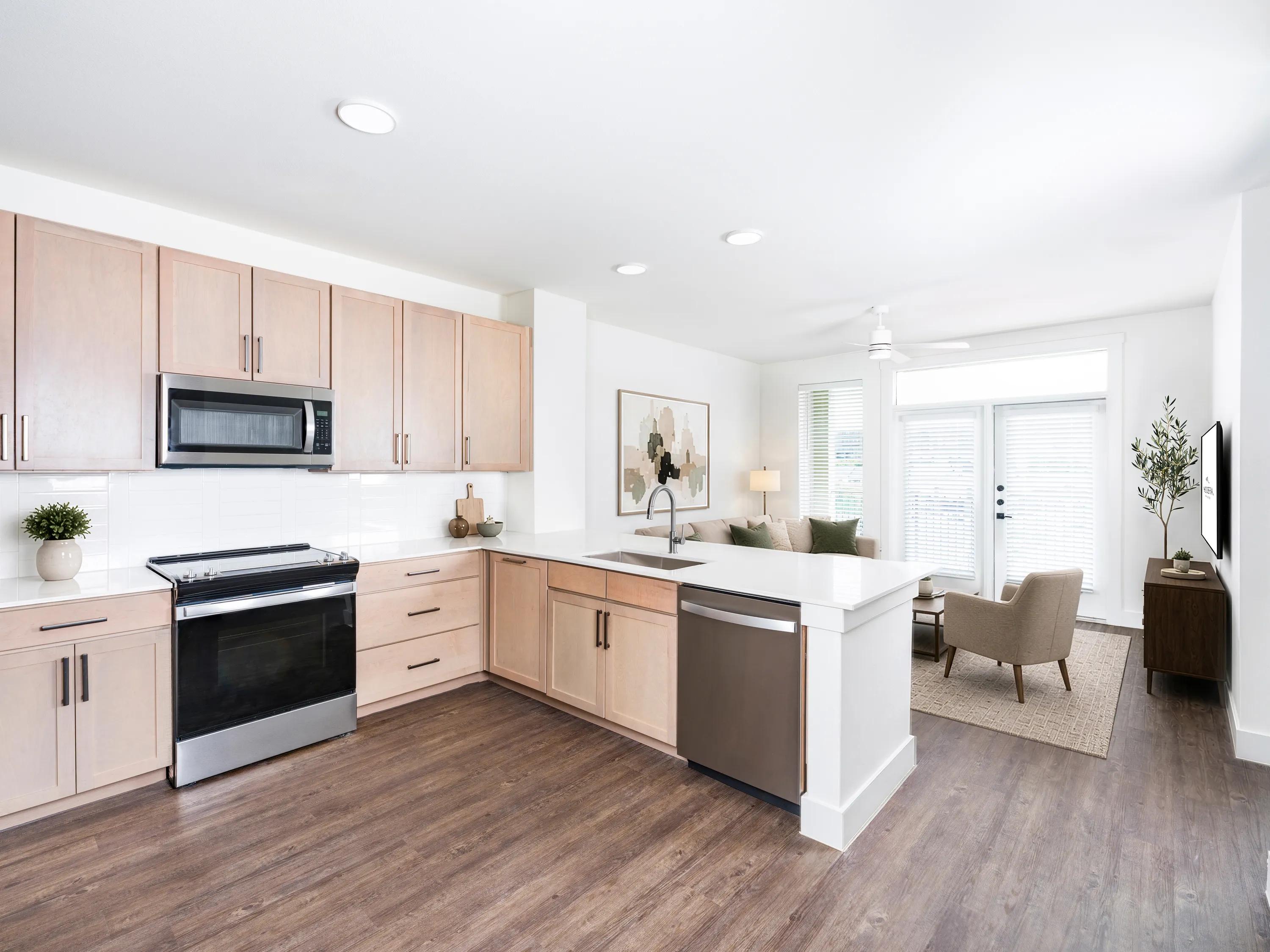 Open kitchen with light wood cabinetry, a spacious island modera trailhead apartment homes for rent in dallas texas