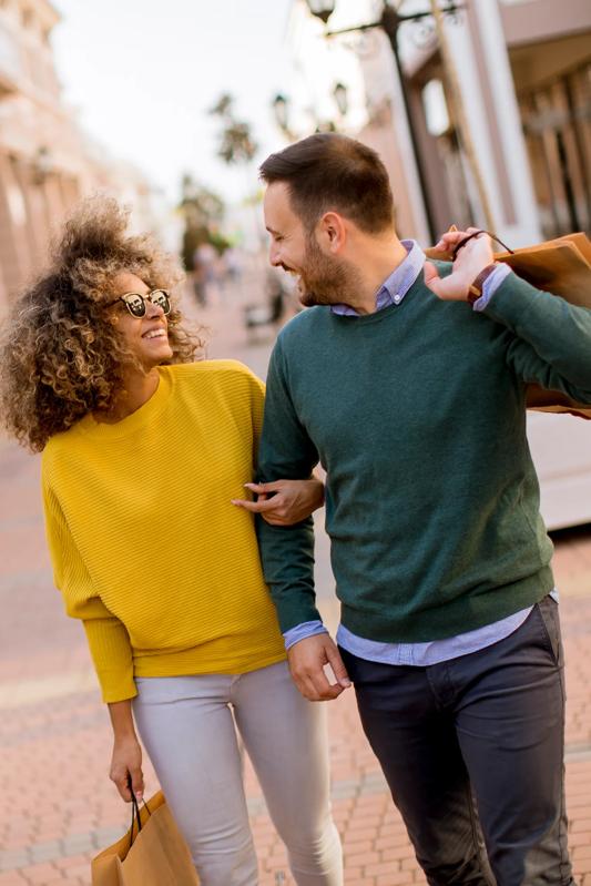 younger couple shopping and smiling while walking through downtown
