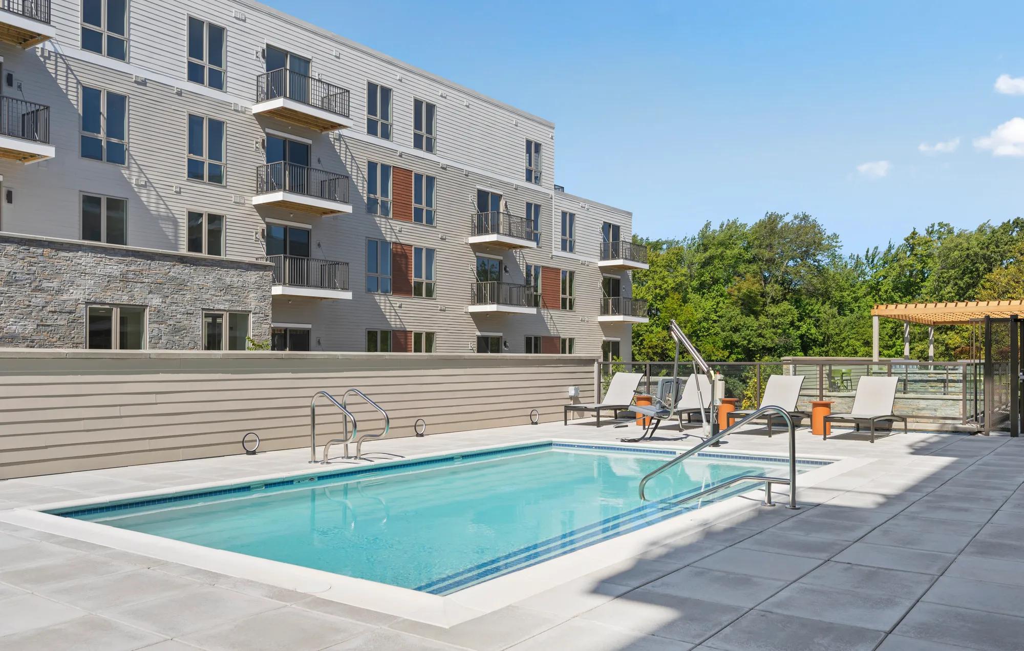 pool deck looking onto greenspace on sunny day at modera newton apartment homes for rent in ma