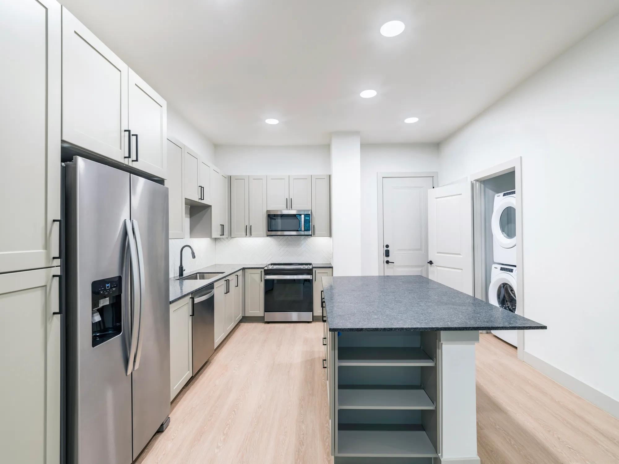 long view of kitchen with wood plank style flooring and washer dryer in adjacent closet modera mckinney ridge apartment homes for rent in tx