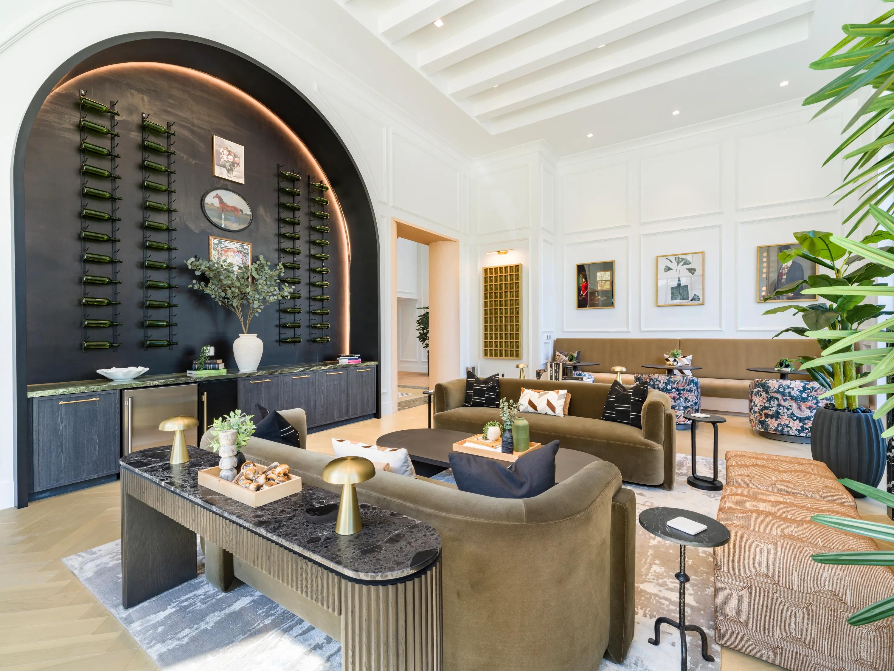 Elegant living room with modern decor, featuring plush green sofas, a chic fireplace, and large windows offering a serene view.