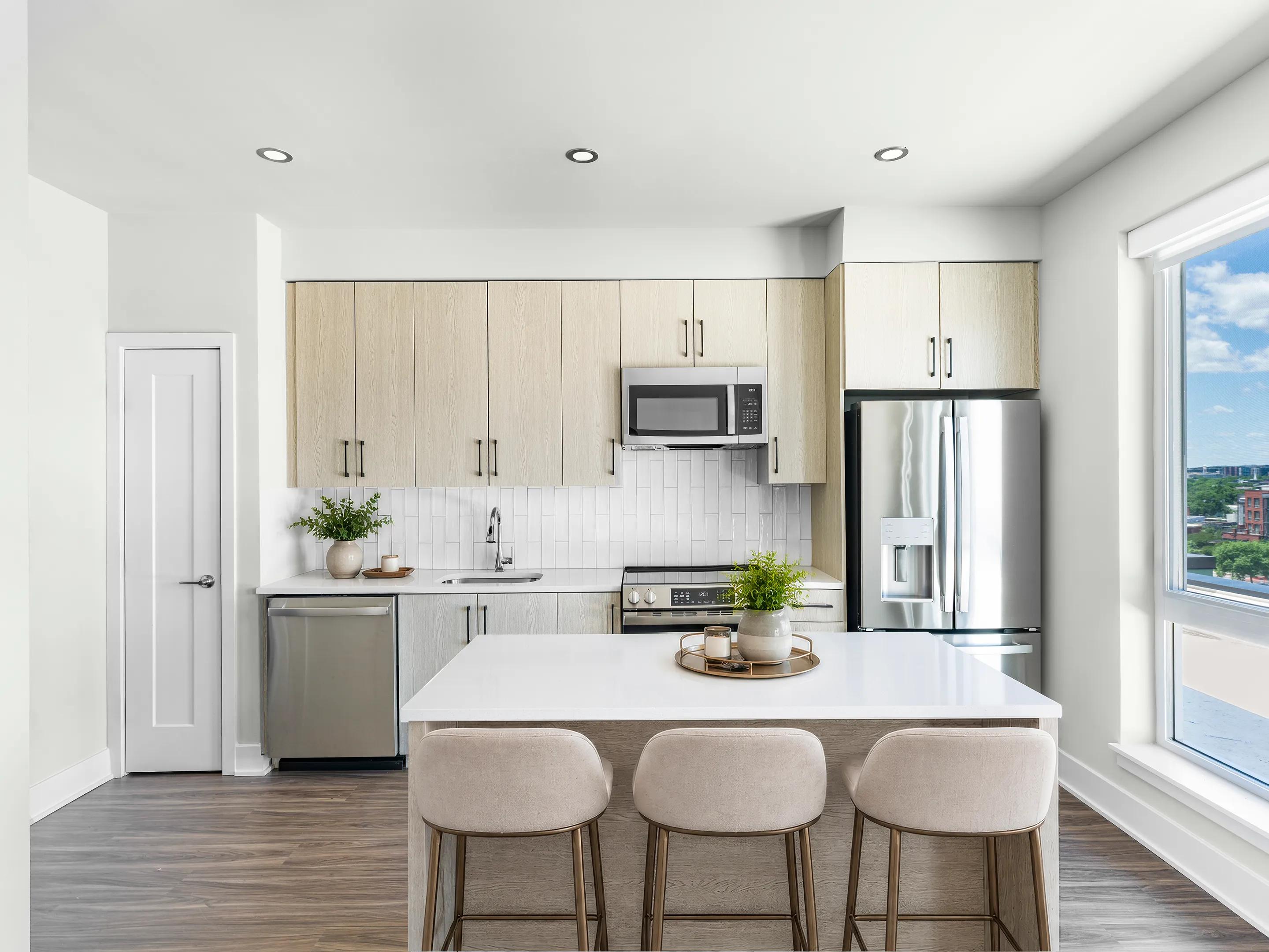 bright kitchen with full-height cabinetry, quartz island seating, and large windows modera h street apartments washington dc
