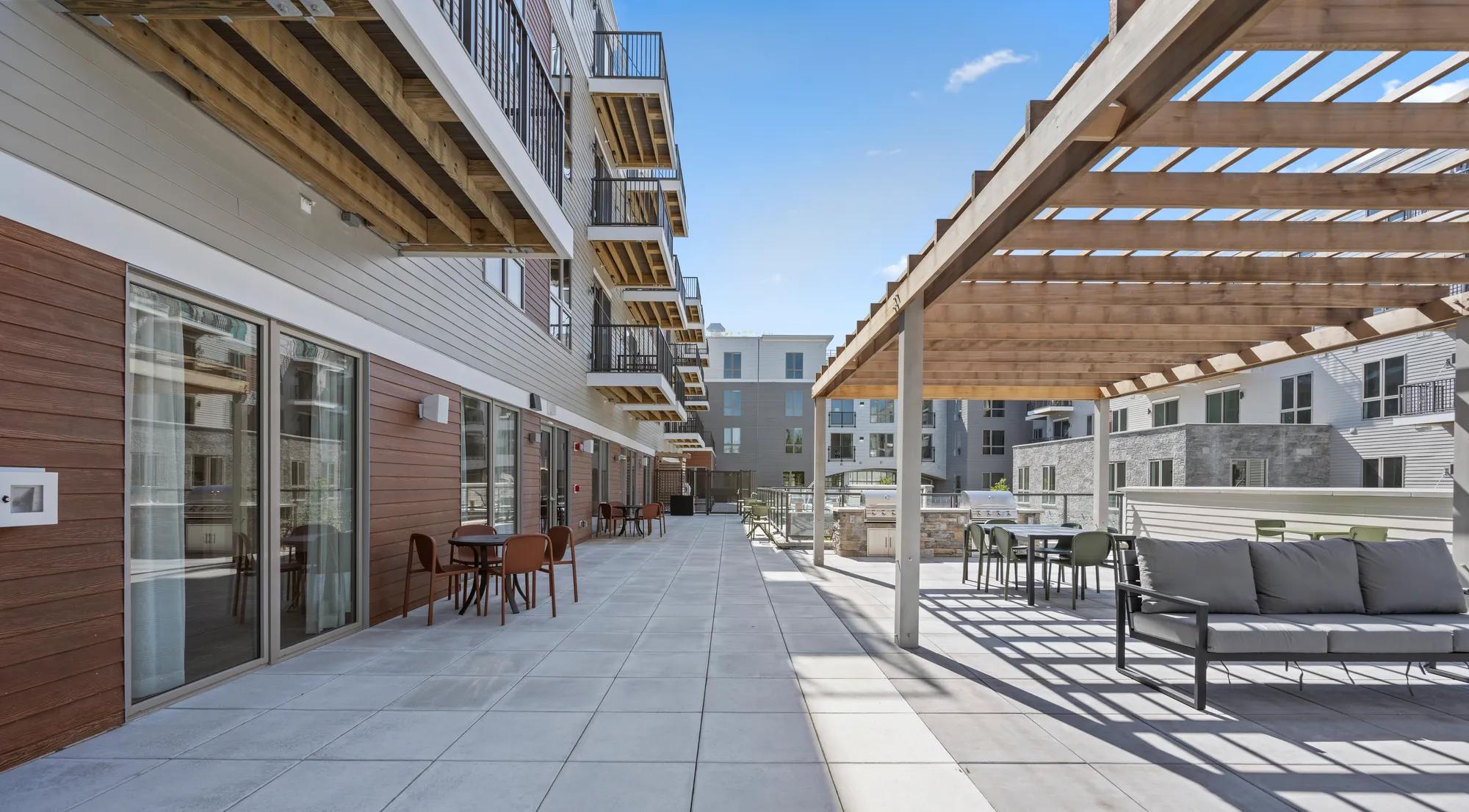 courtyard space with dining tables and bbq grills at modera newton apartment homes for rent in ma
