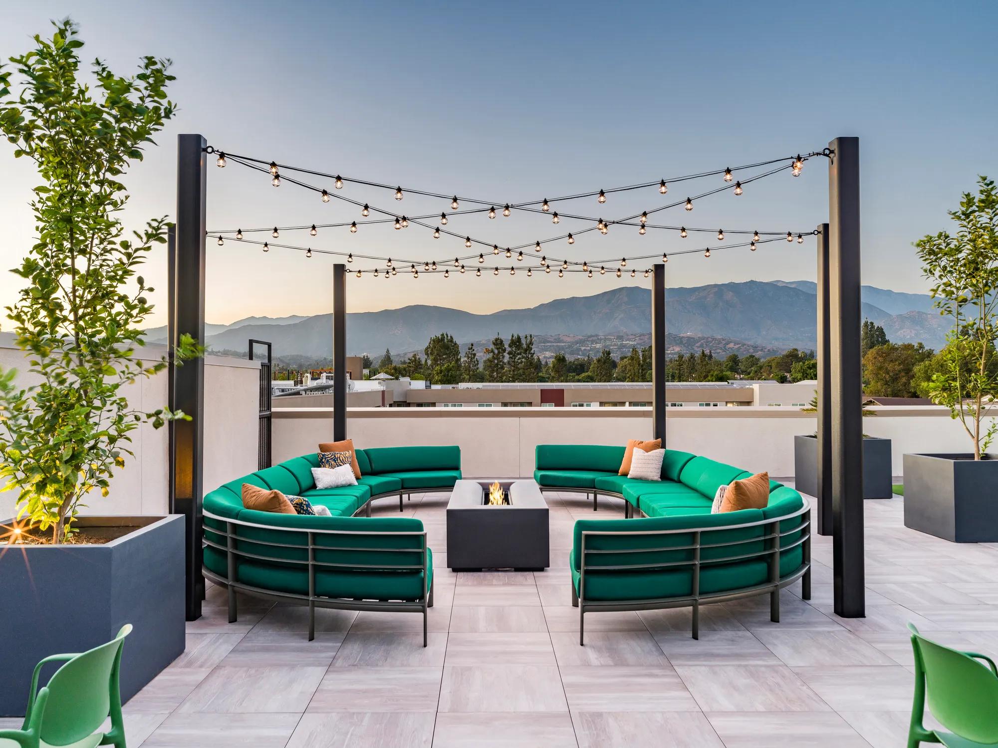 Outdoor rooftop deck with circular sofas encircling a fire table at Modera Pomona apartments for rent in ca