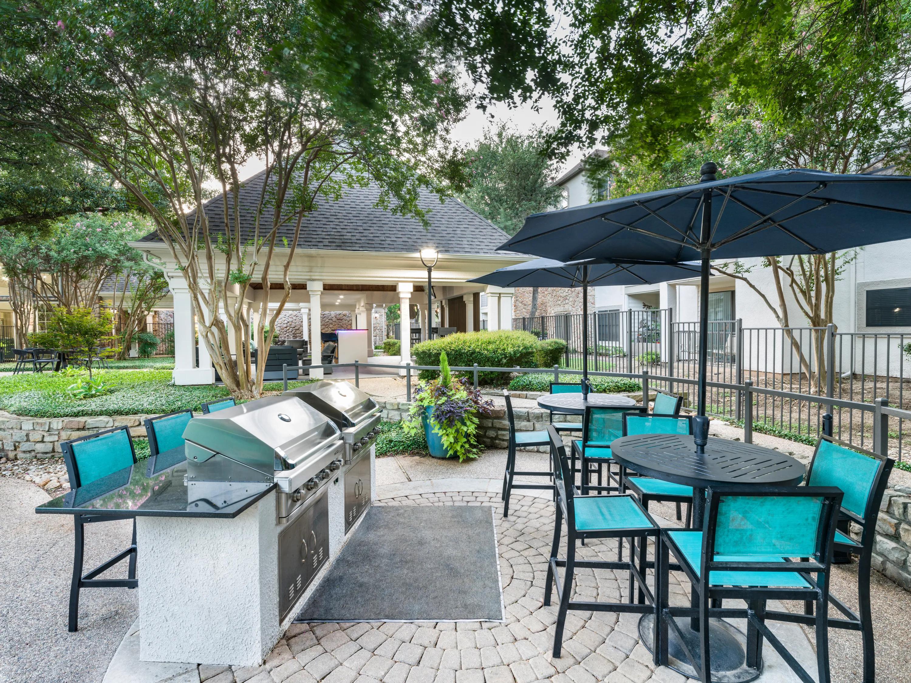 bbq area with outdoor tables next to pool alister sunset valley apartment homes for rent in austin tx
