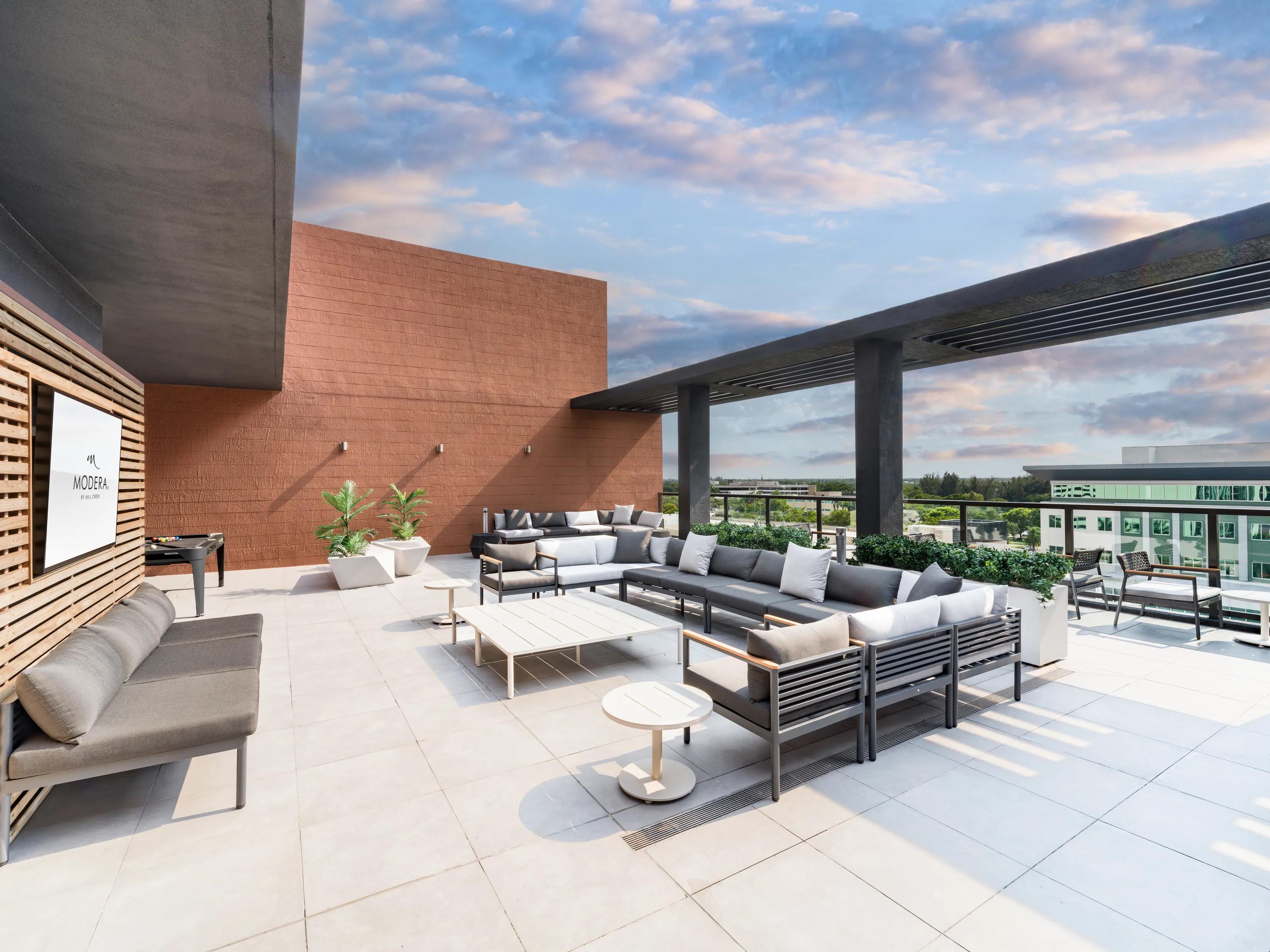 Rooftop terrace with shaded lounge seating, open-air gathering areas modera coral springs phase 2 apartments in coral springs fl