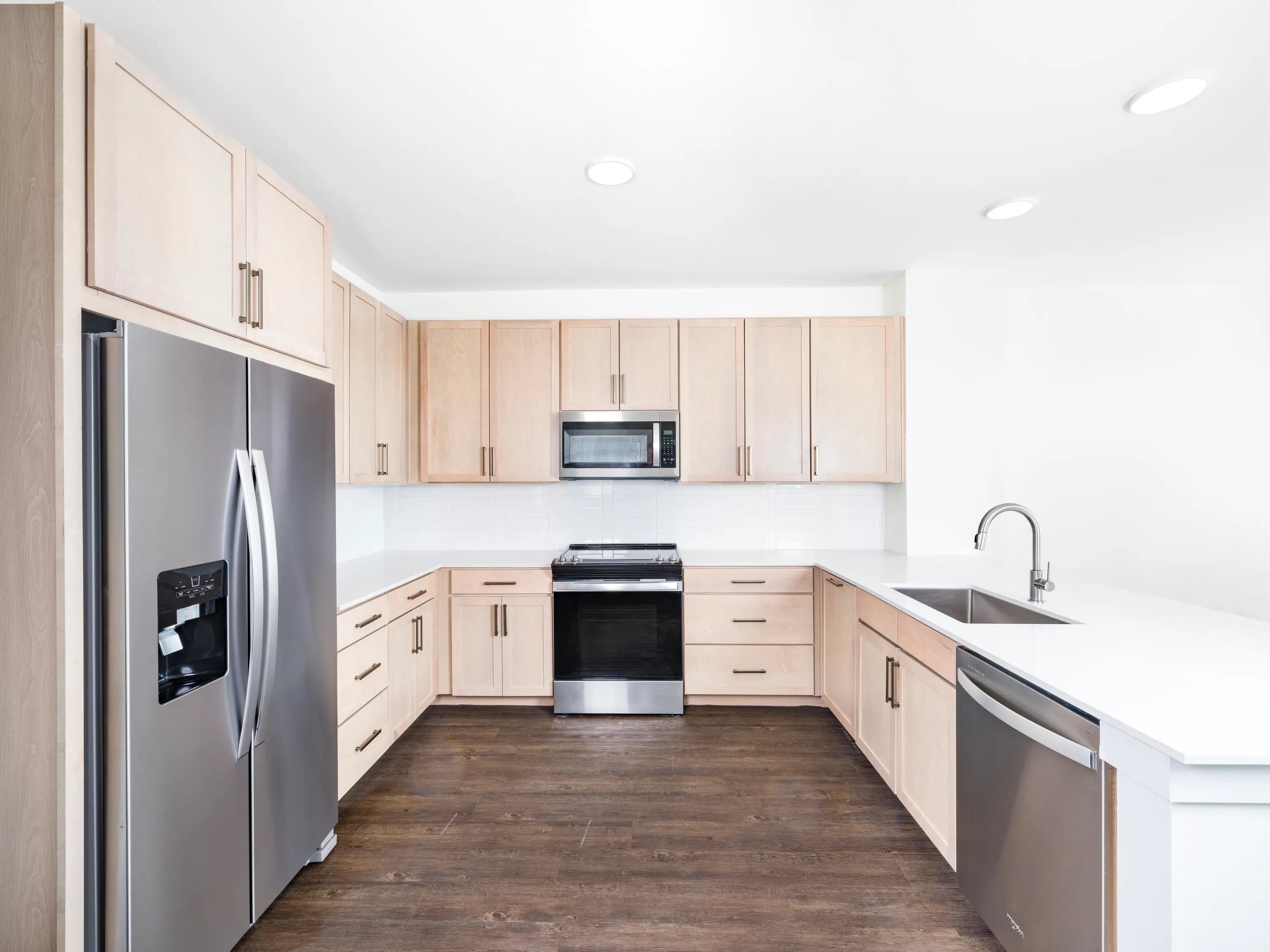 U-shaped kitchen with light wood cabinetry, quartz countertop modera trailhead apartment homes for rent in dallas texas