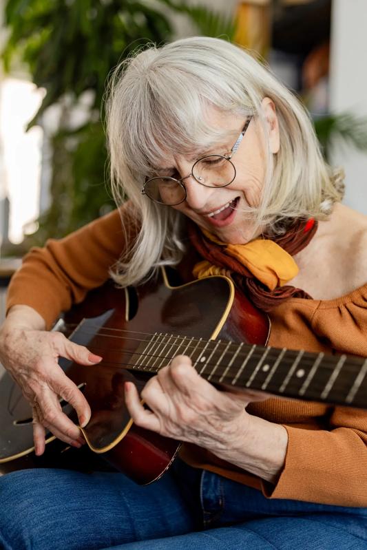 mature adult sitting down playing guitar smiling modera mcgavock apartments in nashville tn