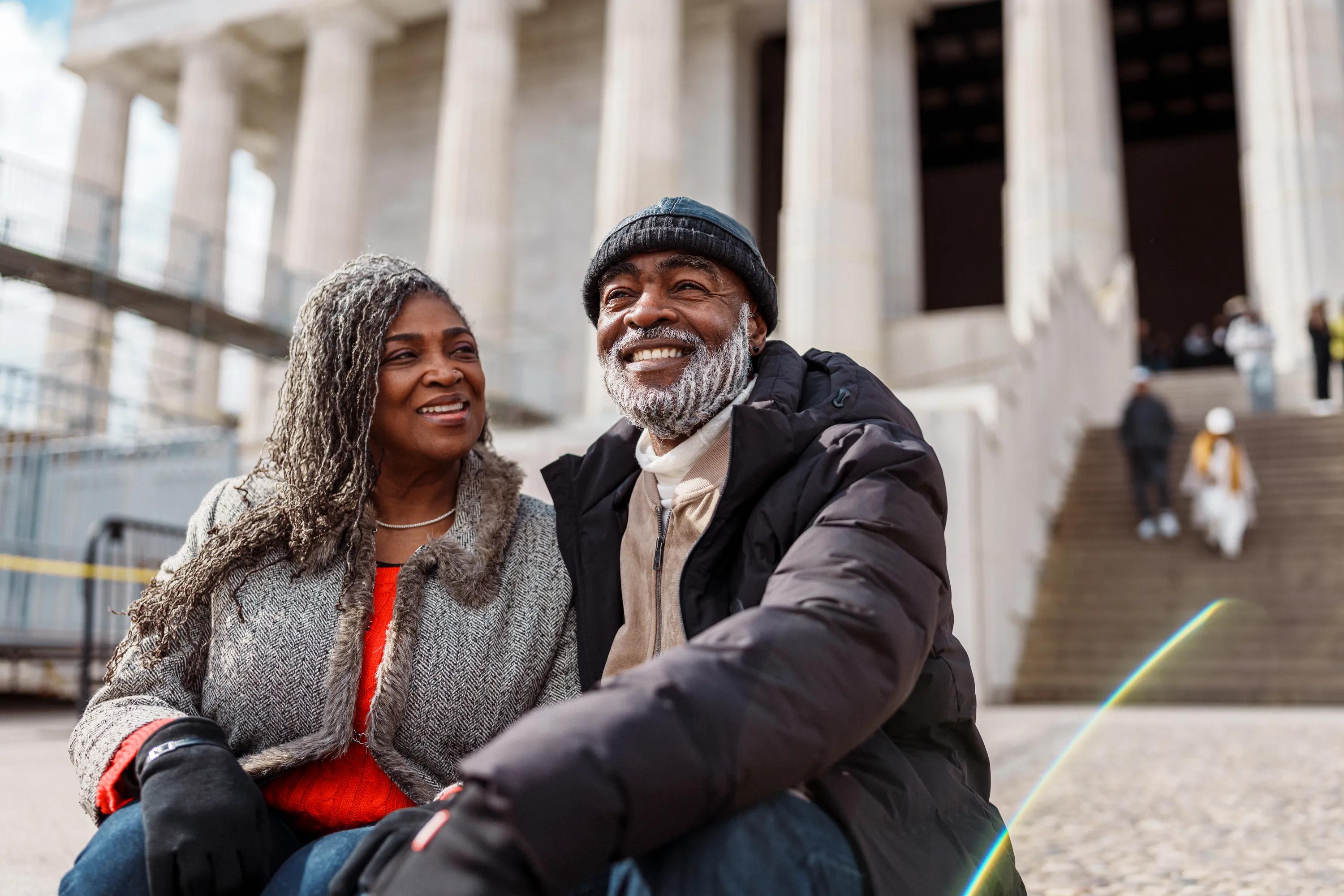 man and woman sitting on steps of large building smiling modera h street apartment homes for rent in washington dc