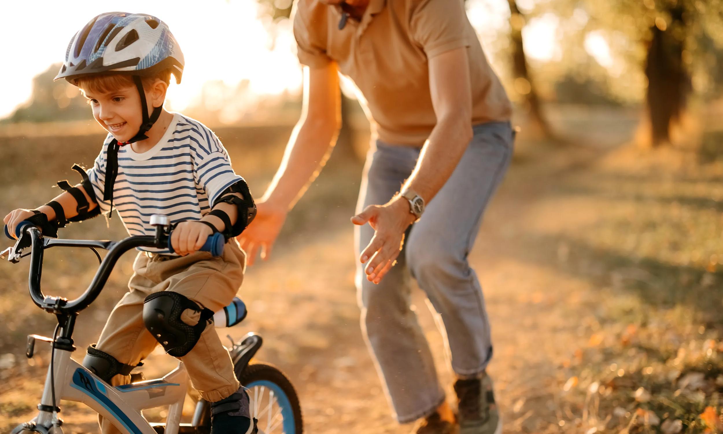young child learning to ride a bike with parent modera rigeline apartments in mkcinney tx