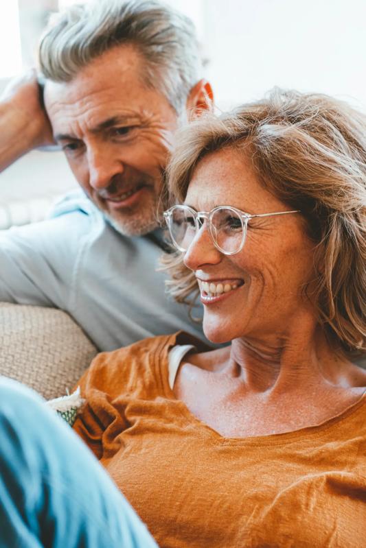 couple sitting on couch holding wine glasses and smiling